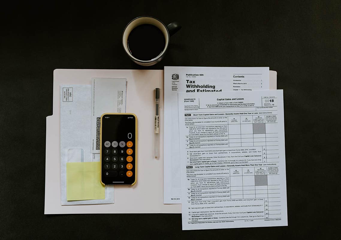 Des formulaires administratifs, une calculatrice et un stylo sur un bureau